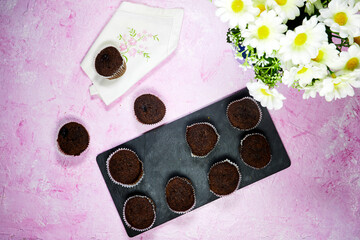 homemade chocolate muffins in black board plate with daisy flowers vase
