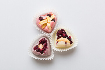 chocolate sweets in the form of a heart with fruits and nuts on a colored background. top view with space for text, holiday concept