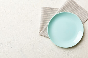Top view on colored background empty round blue plate on tablecloth for food. Empty dish on napkin with space for your design - obrazy, fototapety, plakaty