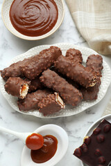 Tasty chocolate bars with caramel on white marble table, flat lay