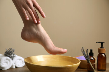 Woman holding her foot over bowl with water, closeup. Pedicure procedure