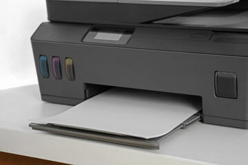 Modern printer with paper on white table, closeup