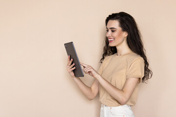 A young woman with a tablet in her hands on a beige background.