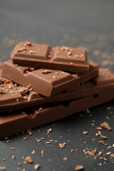 Pieces of tasty chocolate on grey table, closeup