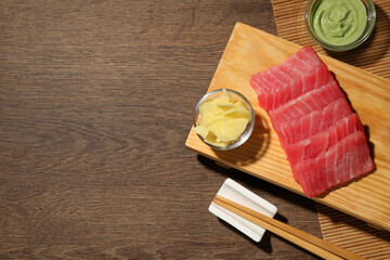 Tasty sashimi (pieces of fresh raw tuna) served with wasabi sauce and ginger slices on wooden...