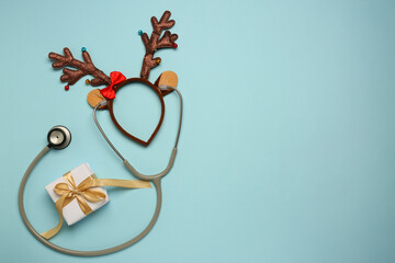 Greeting card for doctor with stethoscope, gift box and reindeer headband on light blue background,...