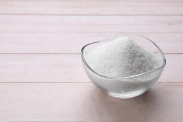 Granulated white sugar in bowl on wooden table, closeup. Space for text