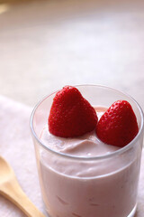Bowl of strawberry yogurt with two fresh strawberries on the top. Selective focus.
