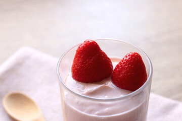 Bowl of strawberry yogurt with two fresh strawberries on the top. Selective focus.