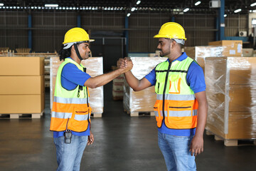 Happy smiling teamwork in hardhats and reflective jackets arm wrestling celebrate successful together completed deal commitment at retail warehouse logistics, distribution center, success concept