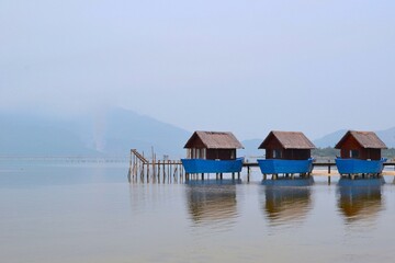 Wooden fishermens huts built on a calm lake with pier and mountains in the background