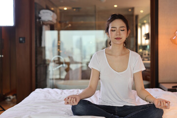 Asian woman wearing white sleepwear practicing mediate yoga. Lifestyle concept.