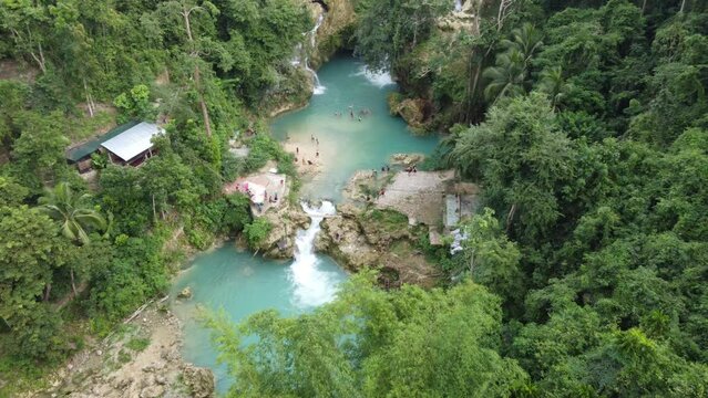 Aerial location reveal of Kawasan falls canyoneering activity in Cebu, Philippines. Ascending Dolly shot backwards