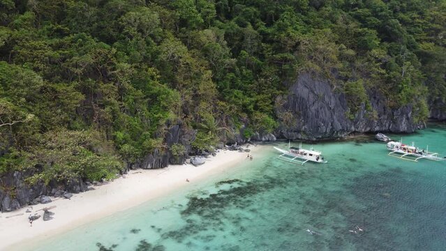 Island-hopping Tour Boats with People snorkeling at Paradise Beach of Cadlao Island, El Nido. Aerial