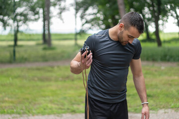 Fototapeta premium Close up photo of a young man holding a jump rope and training outside 