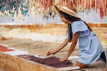 Cute little girl with decorative dried ears of corn and straws