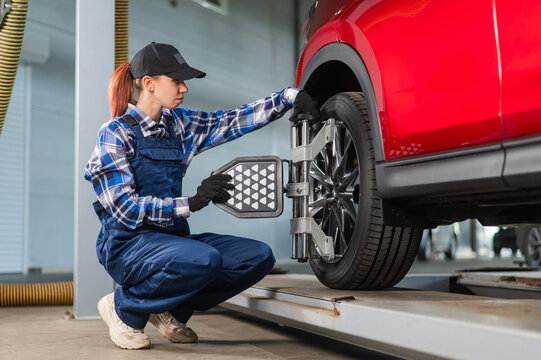 A female auto mechanic makes a camber. Woman working in a car service.