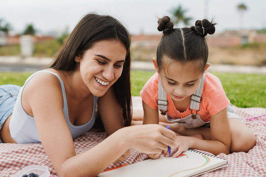 Happy teenage girl painting with little sister at park during summer time - Family concept