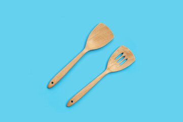 Wooden kitchen spatula on blue background.