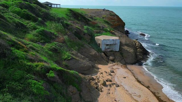pillbox firing point on the sandy shore of the blue sea - Aerial flying drone video  