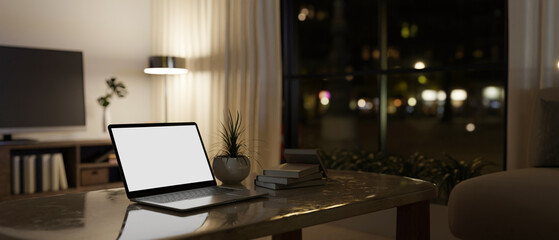 A laptop mockup on a coffee table in modern contemporary living room at night.