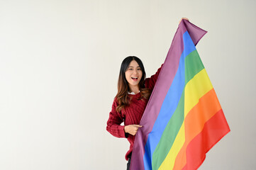 A happy young Asian woman holding a rainbow LGBT flag. LGBTQ+ pride month