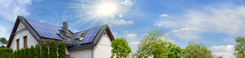 Modern house with solar panels. Clear sky, sun. Web banner, copy space.
