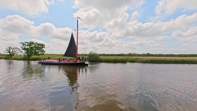 The traditional Norfolk wherry Albion transporting passengers along the River Bure, Norfolk Broads. Captured on a bright summer day