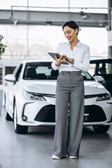 Young saleswoman with tablet in a car showroom