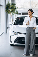 Young saleswoman with tablet in a car showroom