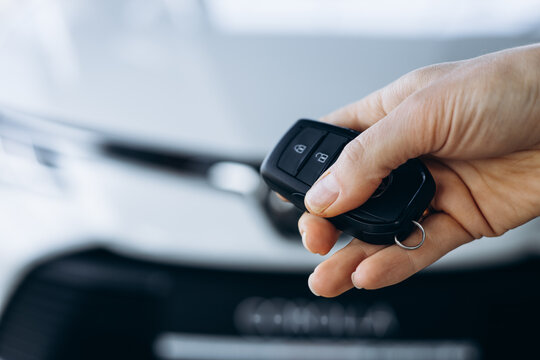 Woman holding car keys by her new car close up photo