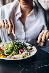 Woman drinking coctail and eating salad in a cafe