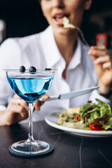 Woman drinking coctail and eating salad in a cafe