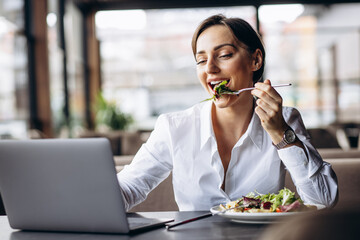 Business woman working on laptop and eating salad