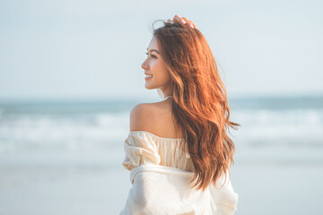 Fototapeta na wymiar Summer beach vacation concept, Carefree young asian woman relaxing at tropical sea beach during summer vacation, Smiling female enjoying breeze and looking at beach.
