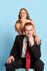 Happy young couple. Beautiful woman and handsome man in stylish clothes posing with smile against blue studio background. Concept of family, relationship, youth, emotions, fun, marriage. Ad