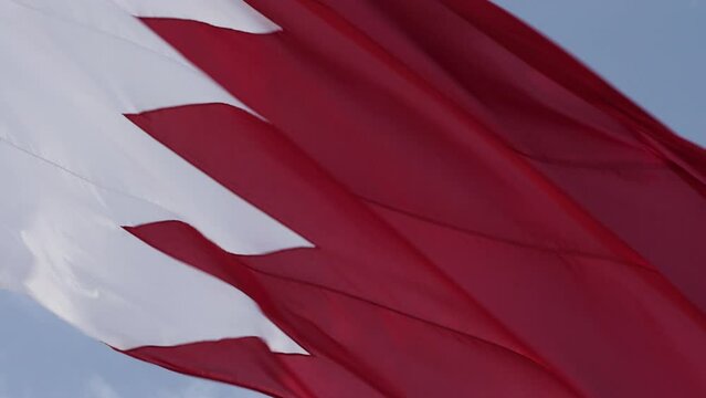 A close-up view of a Bahrain flag against a blue sky.
