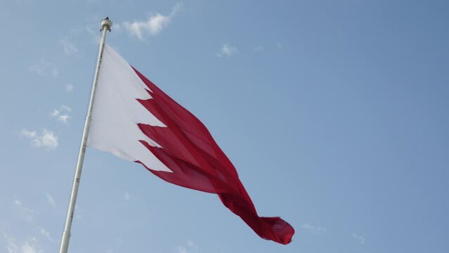 A mid-shot of a Bahrain flag flying against a blue sky.