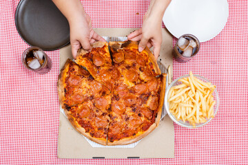 Happy oversize fat Asian women enjoy eating a pizza, hamburger, and French fry with drinking cola soda together. Unhealthy eating and unhealthy lifestyles concept.