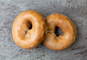 Top close view of a two freshly baked cake donuts on a gray mottled countertop.