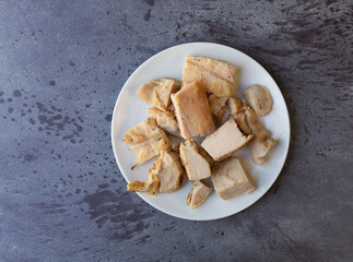 Top view of several pieces of roasted chicken breast on a white plate atop a gray mottled countertop.