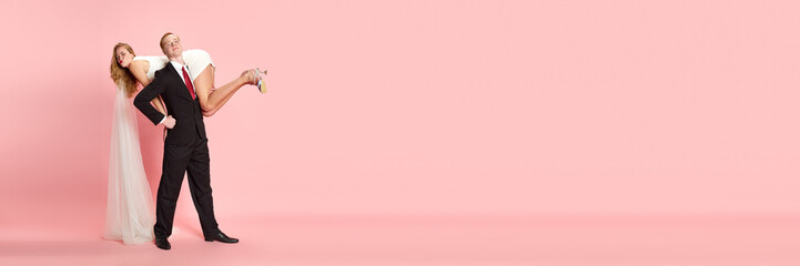 Proud husband. Young man holding woman, wife on his shoulders against pink studio background. Got married. Concept of family, relationship, youth, emotions, fun. Banner. Copy space for ad