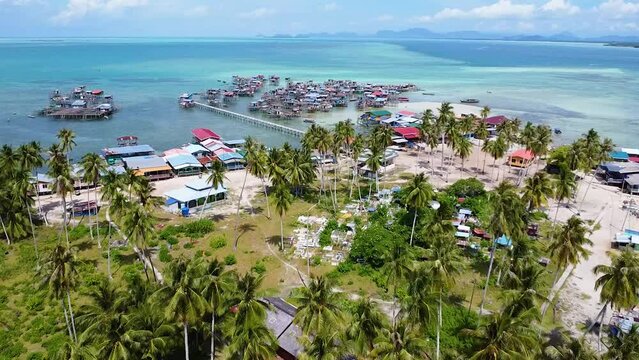 Revealing flyover shot of a Bajau Laut (sea nomads) community from land to their water village in Oulau Omadal, Sabah, Malaysia