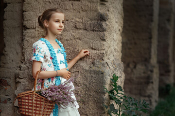 Young pretty girl in vintage elegant dress with bun hairstyle standing with basket of heather...
