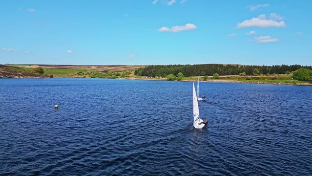 The peaceful Winscar reservoir in Yorkshire transforms into a hub of excitement as small one-man boats take part in a lively sailing event, showcasing the sport's leisurely side.