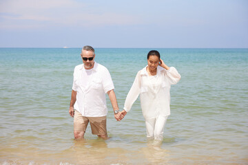 couple holding hands together and walking on the sea