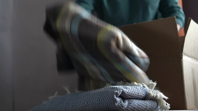 Volunteer stacking warm plaid blankets in a donation box
