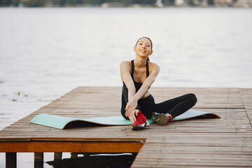 Woman practicing advanced yoga by the water