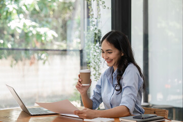 Obraz premium business woman holding a cup of coffee and document at office
