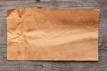 Old yellowed crumpled paper. Blank sheet of paper on vintage wooden back.